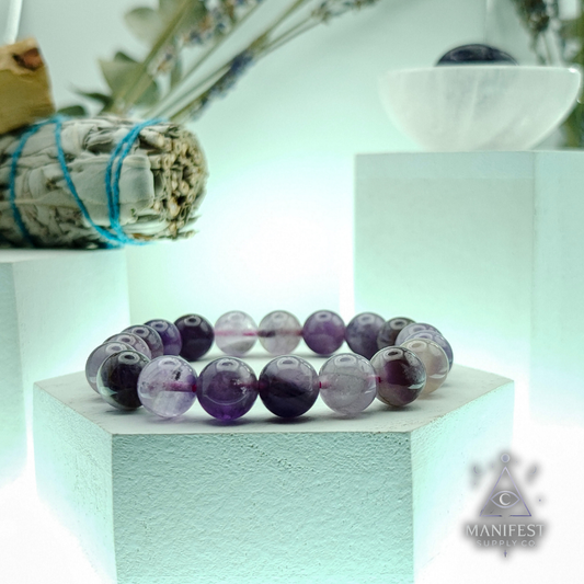 Row of dark green volcanic beads with colorful ones in the background on a light blue surface.