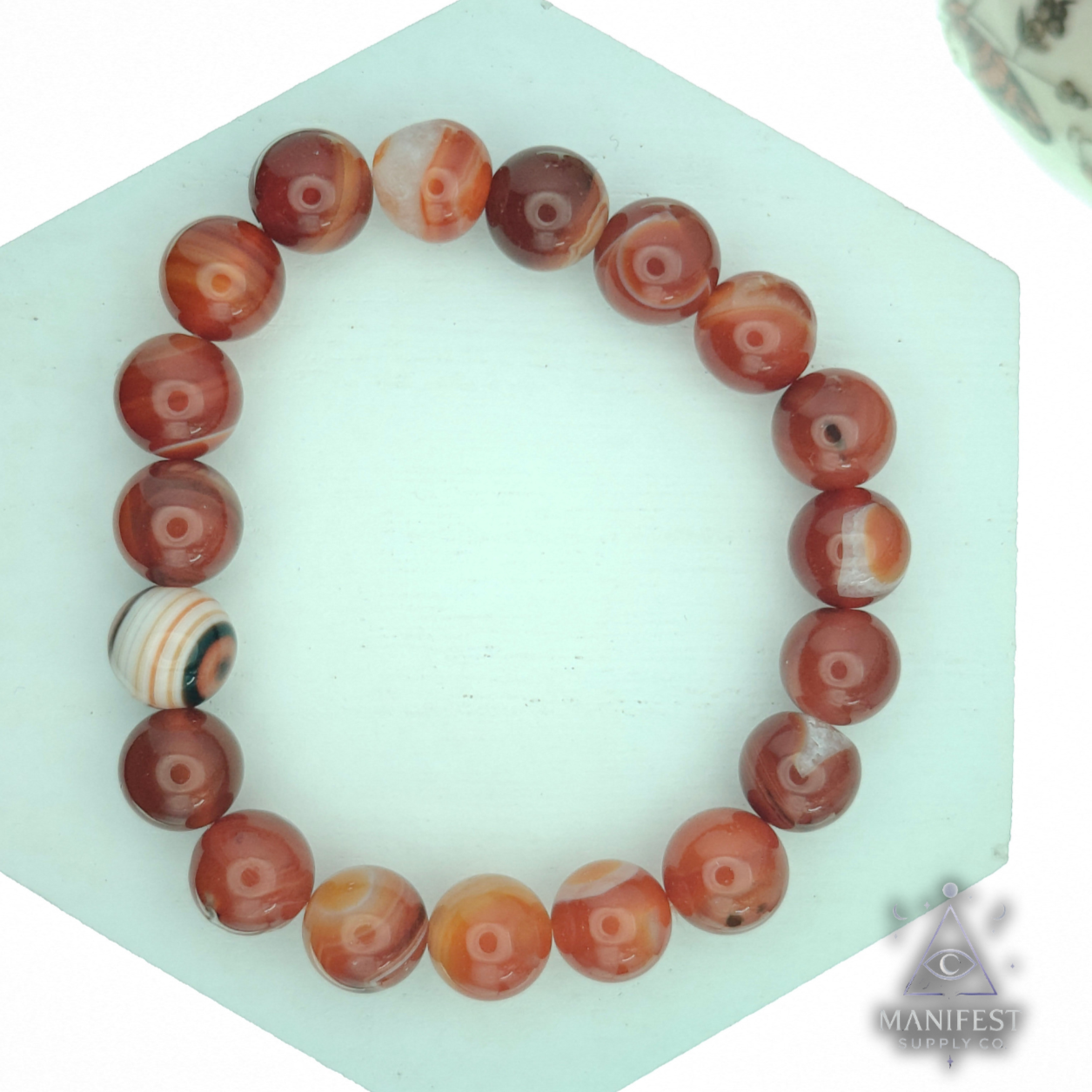 Beaded bracelet on a hexagonal green stand with a white background