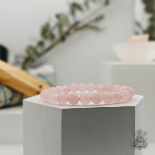 Rose Quartz Pink beaded bracelet on a white hexagonal stand with a blurred indoor background