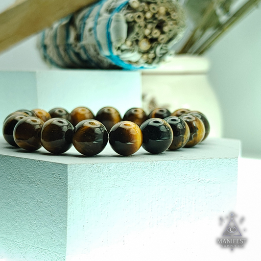 Beaded bracelet with brown and black tiger eye beads on a light blue surface.