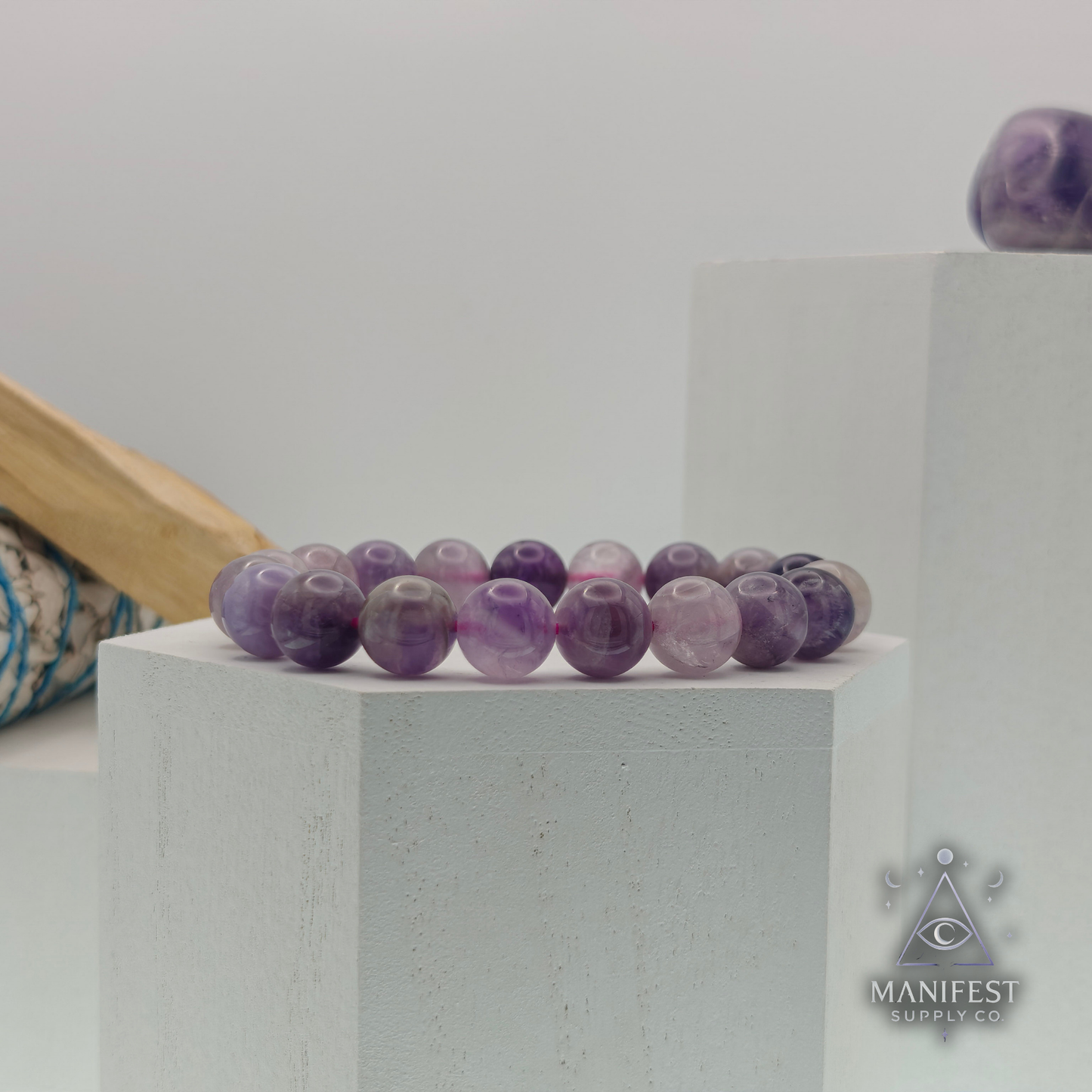 Amethyst beads and colorful end beads on a white hexagonal stand.