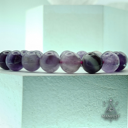 Amethyst bracelet on a light green background with 'Manifest Supply Co' branding.