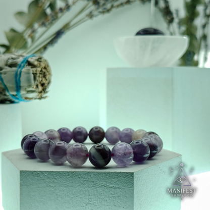 Multicolored beaded bracelet on a white pedestal with a blurred natural background