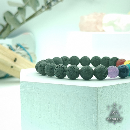 Lava stone bracelet with colorful beads on a light green surface, brand 'Manifest' visible.