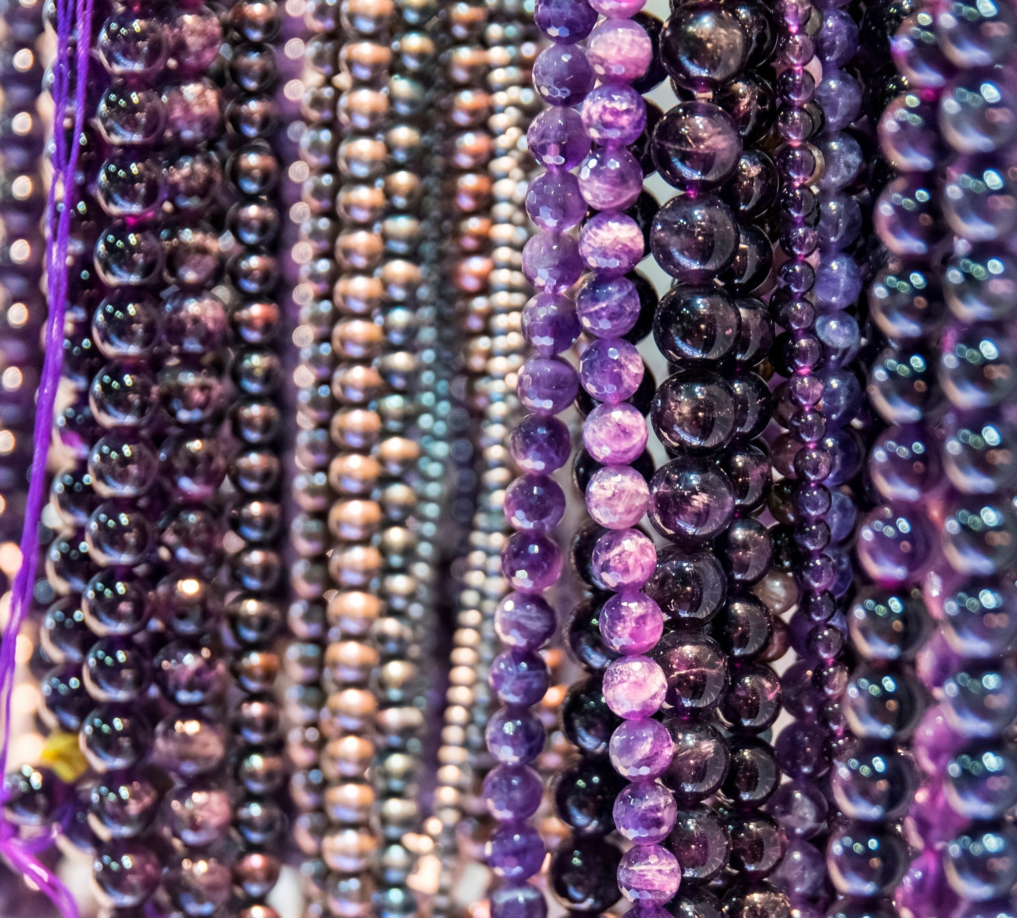 Close-up of energy crystal necklaces with a focus on purple and black beads.