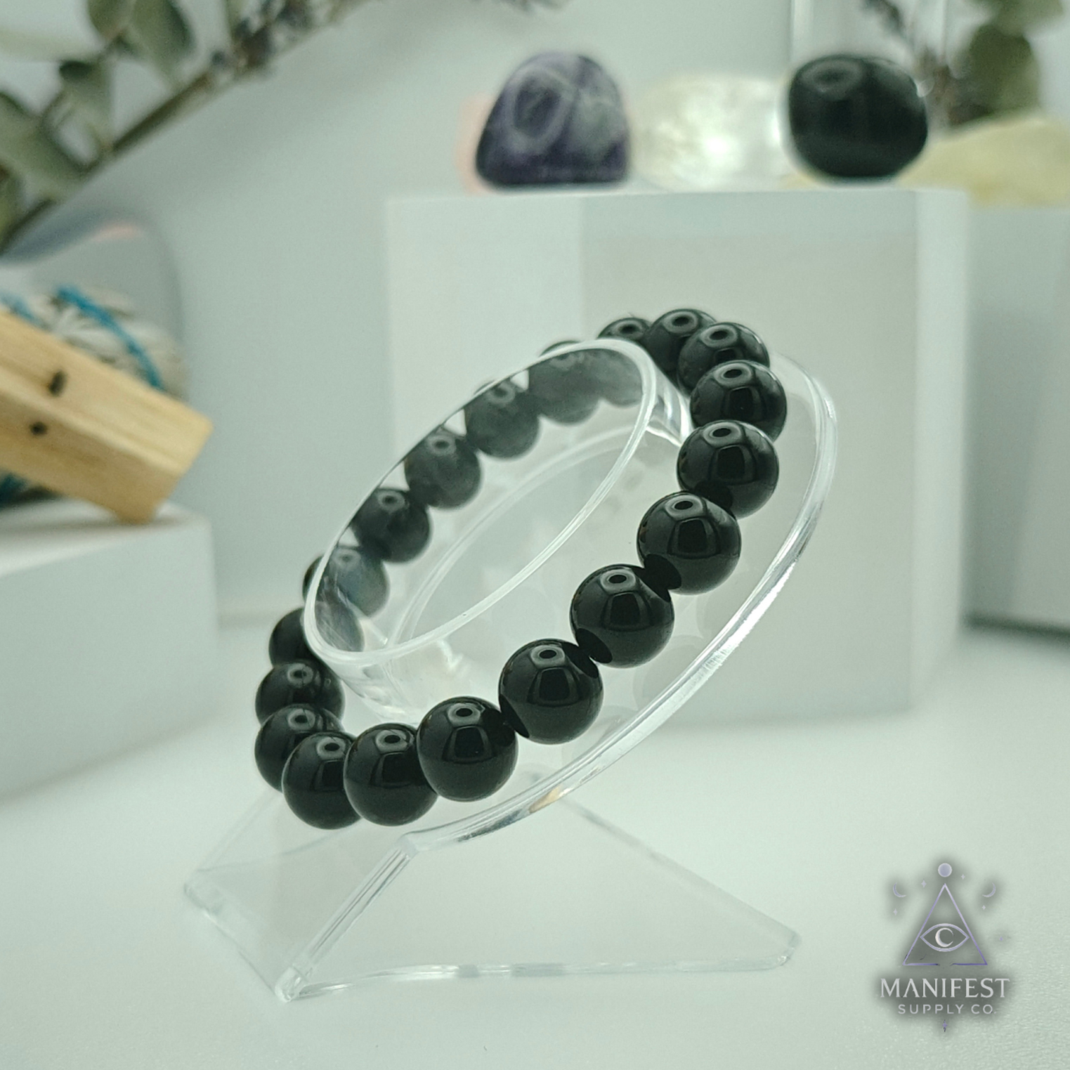 Black beaded bracelet on a clear stand with a blurred background