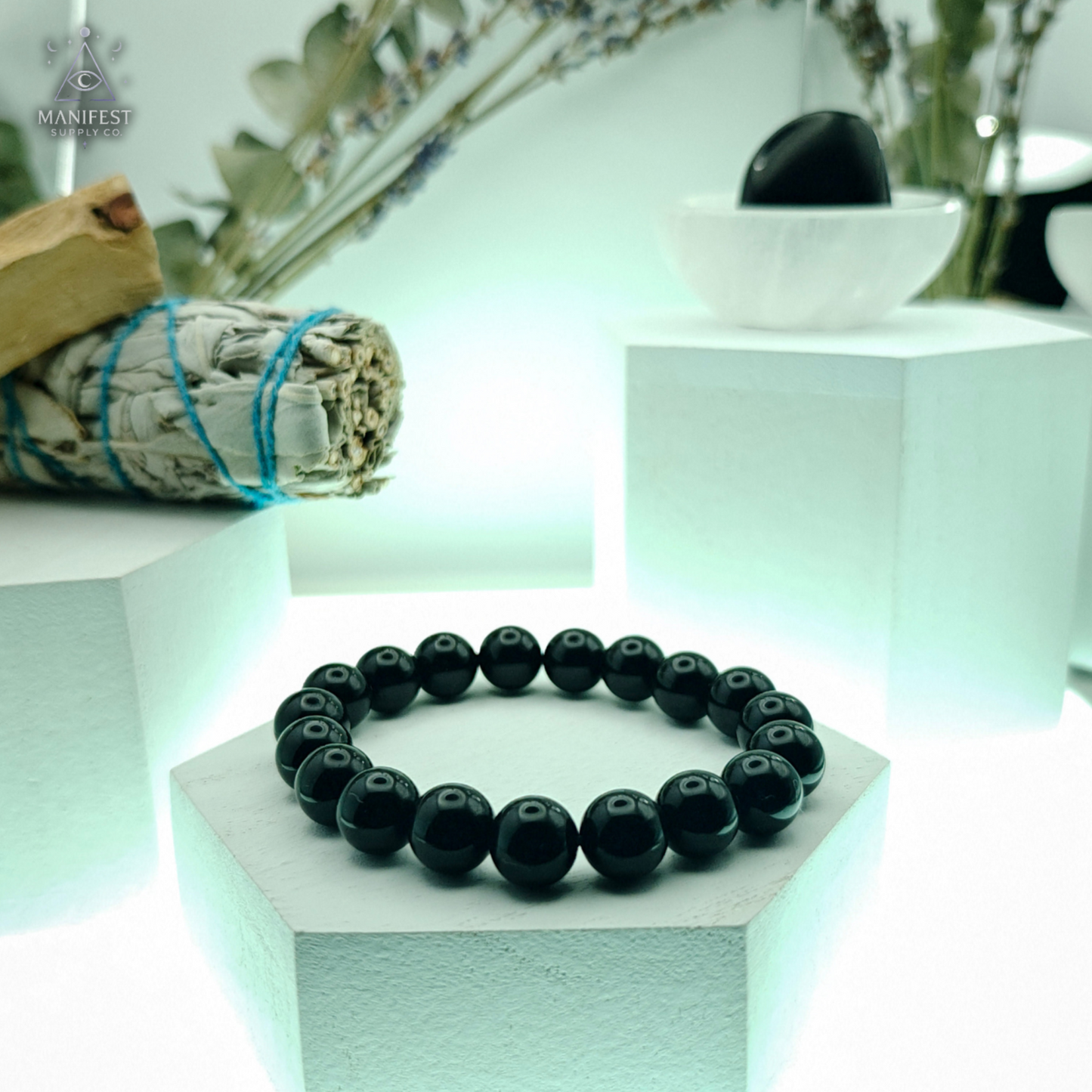 Black beaded bracelet on a white hexagonal stand with a blurred background