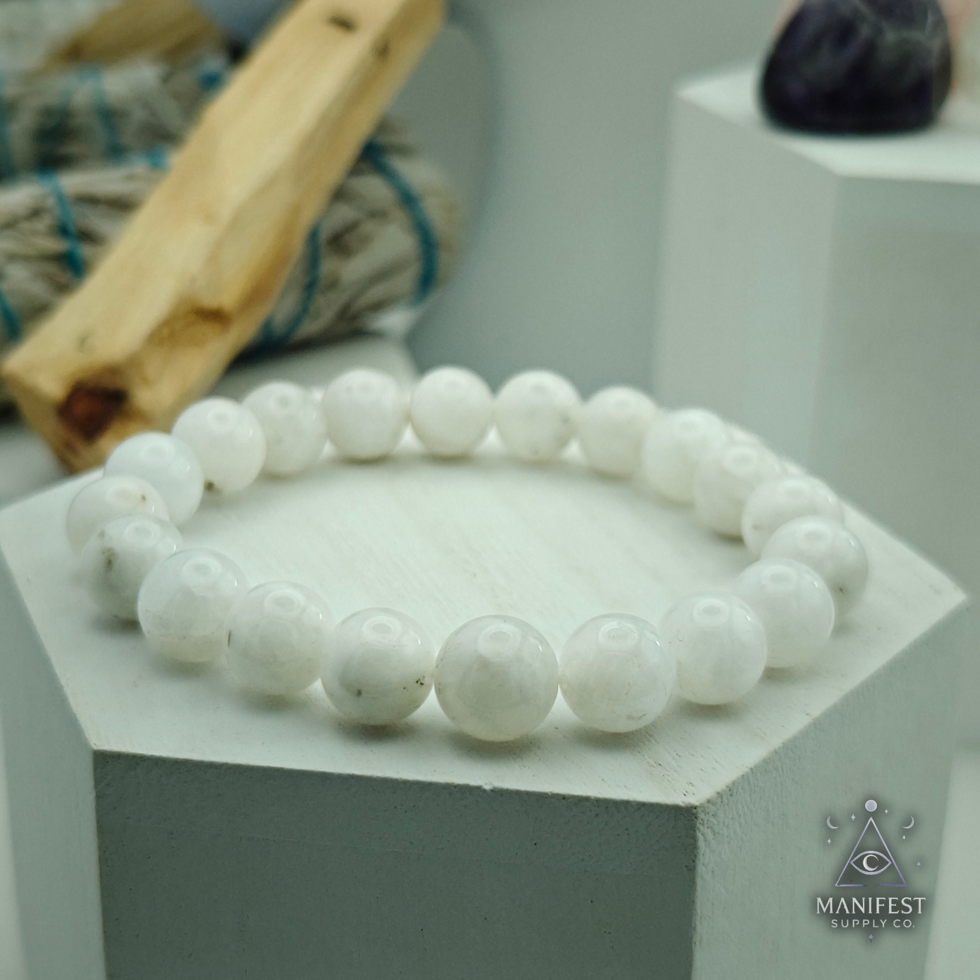 Rainbow Moonstone - 10mm bracelet on a light green background with 'Manifest Supply Co' branding.