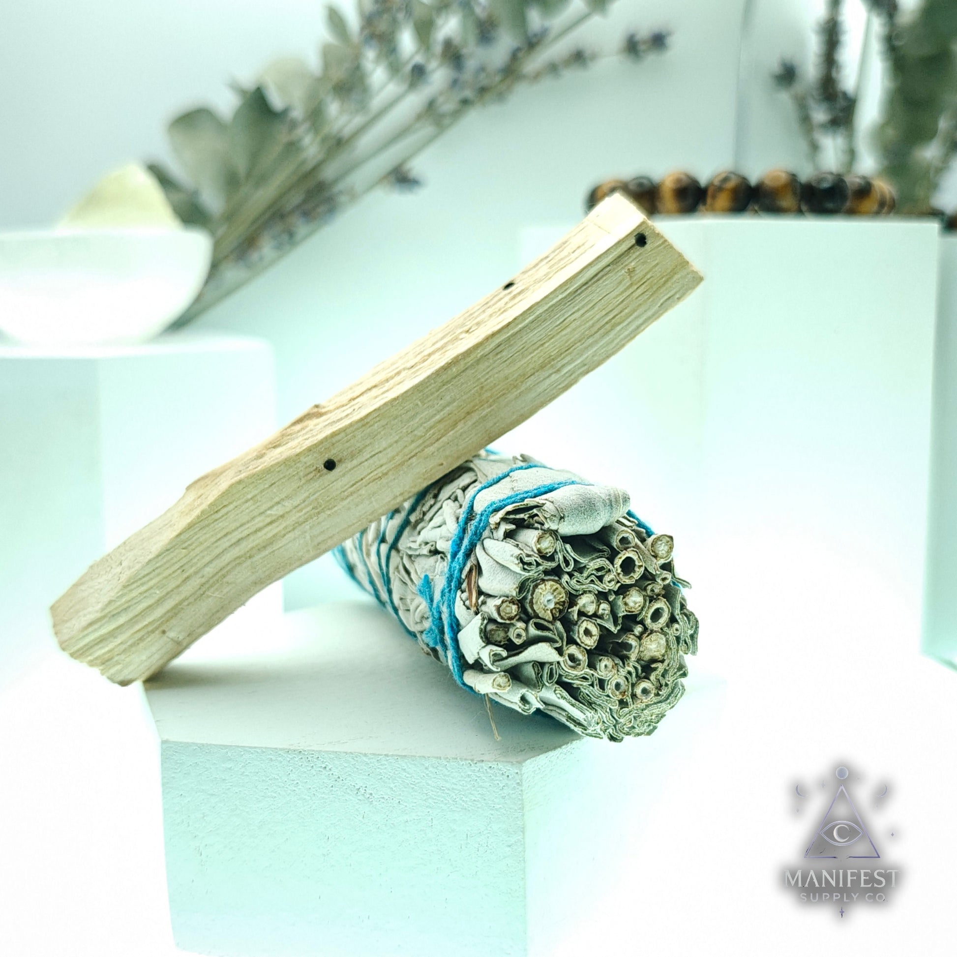 Wooden stick and sage bundle on a light surface with blurred natural background