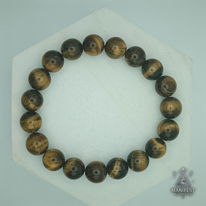 Wooden beaded bracelet on a white hexagonal stand with 'Manifest' branding.